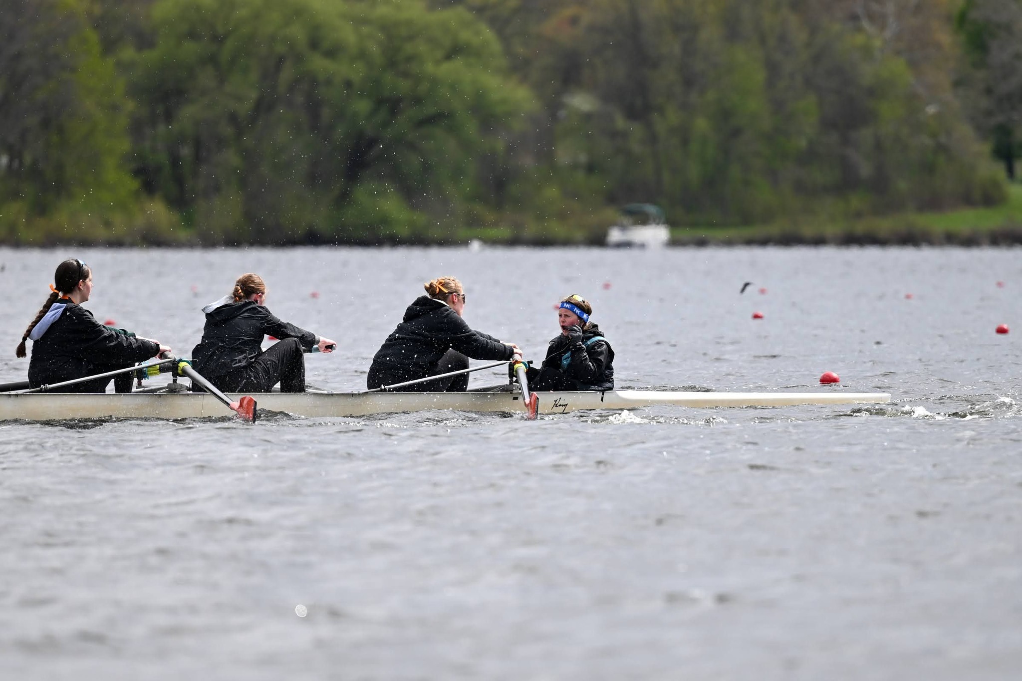 Four teenage girls rowing on choppy water